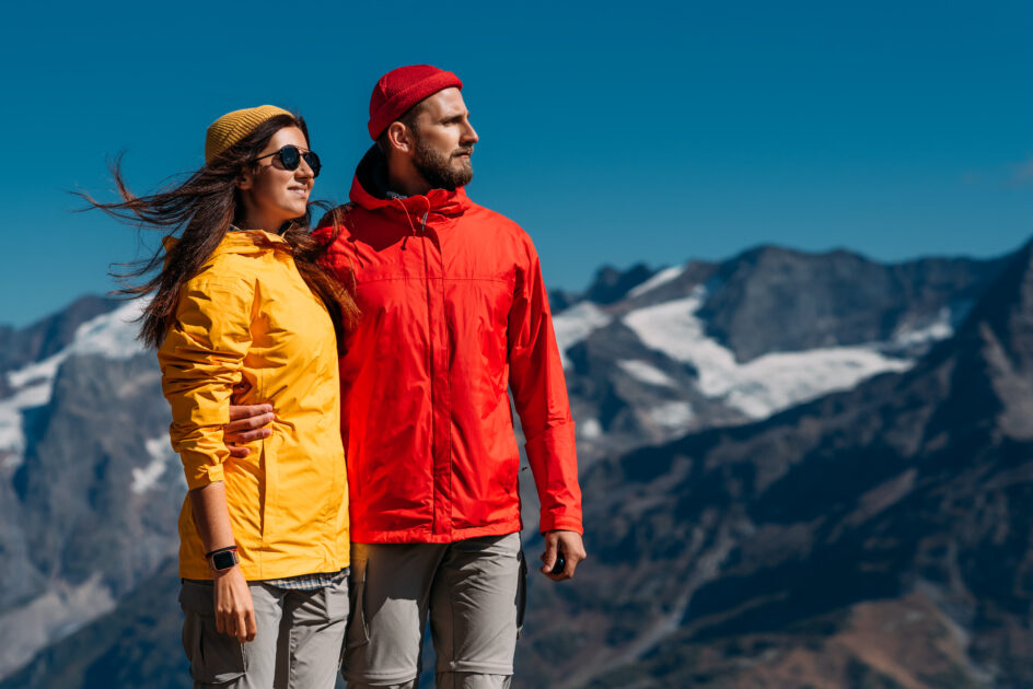 Portrait of travelers in tourist clothes in the mountains. A sporty couple on top of a mountain